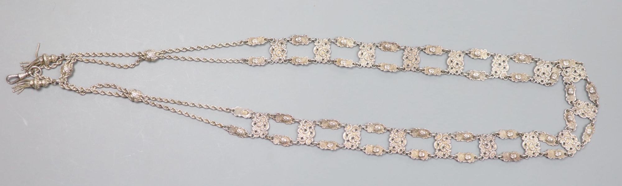 An Edwardian long silver ropetwist chain and openwork panel tassel necklace, with mask decoration